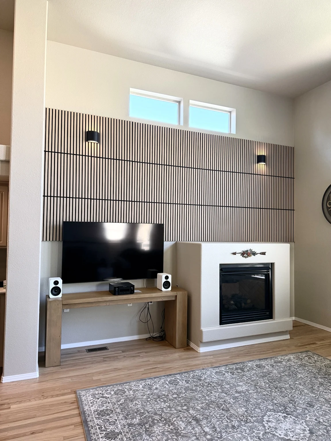 Completed living room with wood-slat wall panels and wall lights